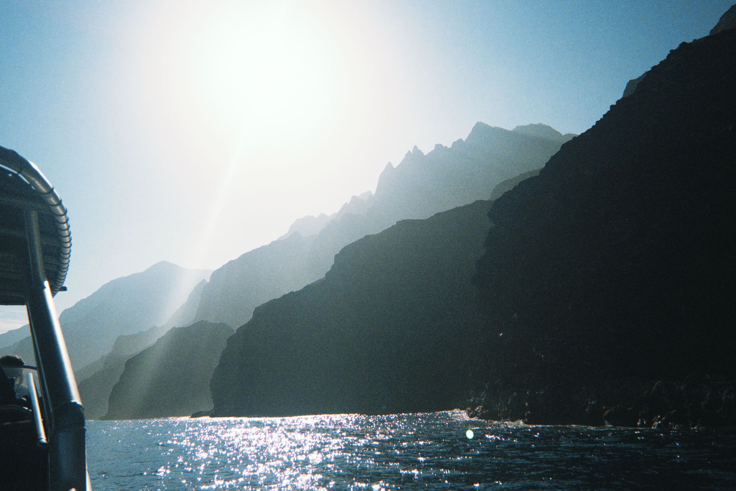 Pacific coastal cliffs at blue hour, backlit by low sun over the sea