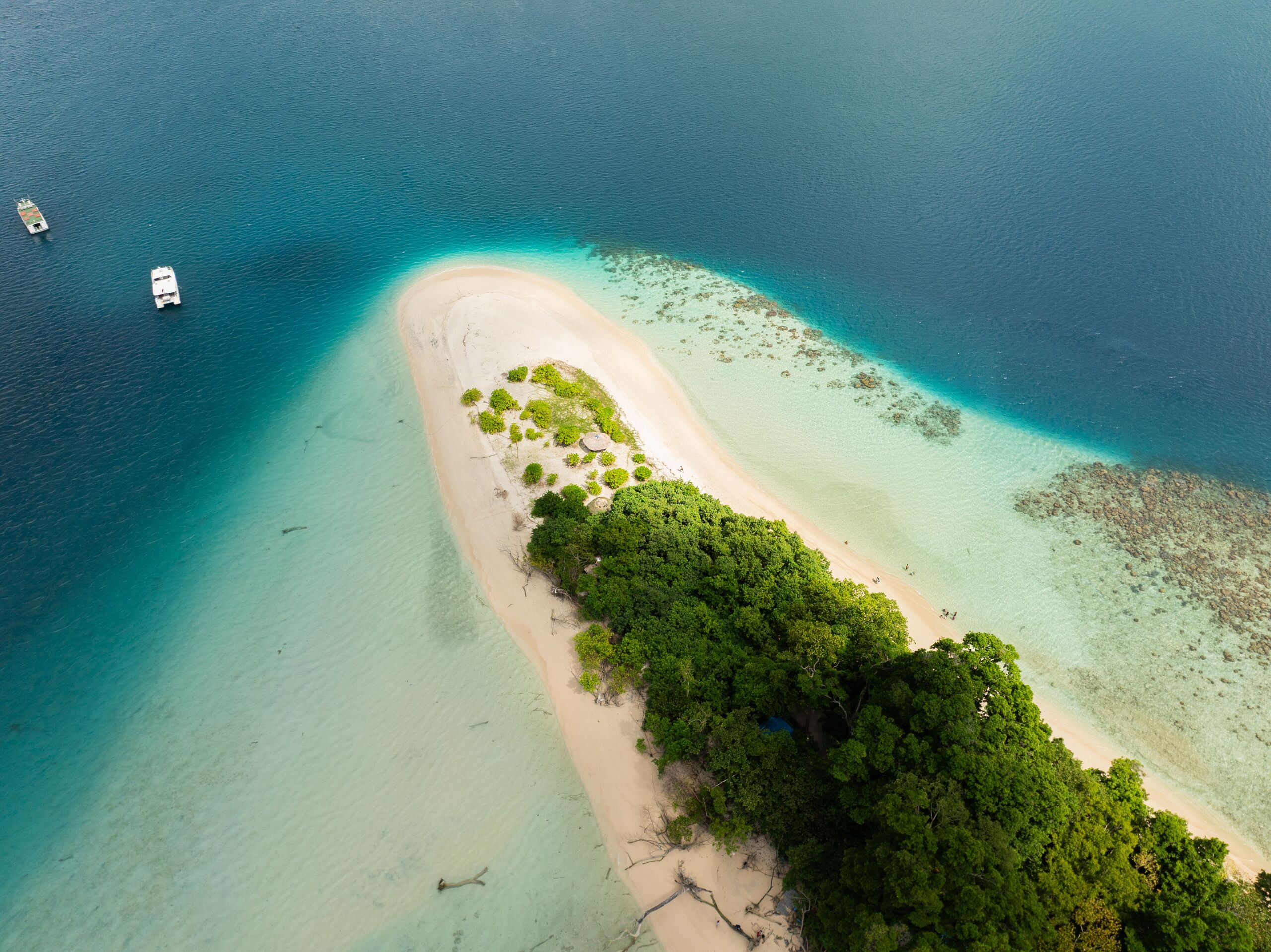 Aerial view of a small Pacific island with a white sandbank and turquoise reef